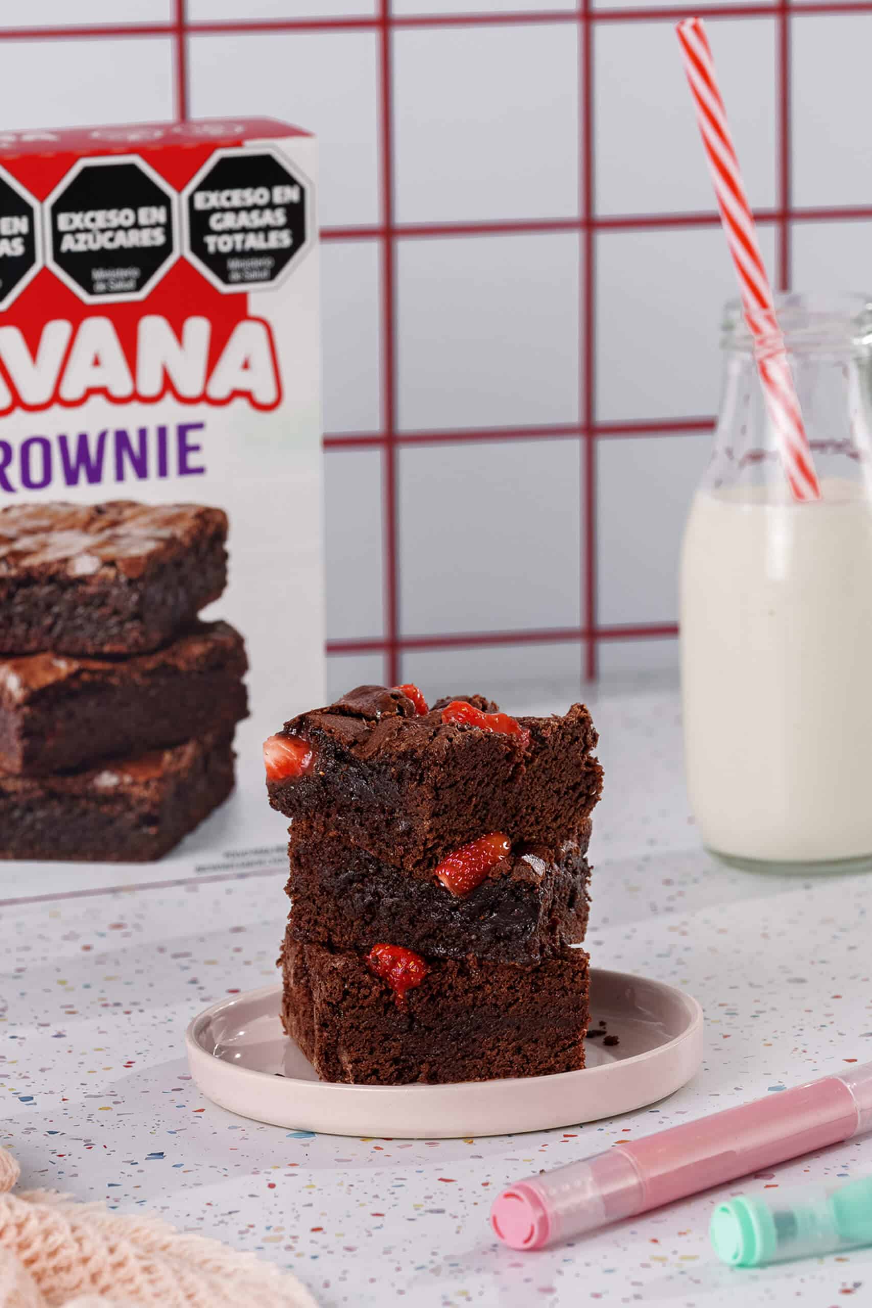 Brownies de chocolate con frutillas frescas en plato blanco.
