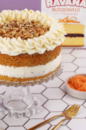 Pastel de zanahoria decorado con crema y nueces, en un soporte de cristal.