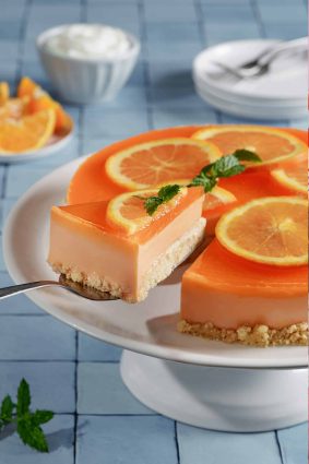 Tarta de naranja con rodajas de naranja y menta decorativa.