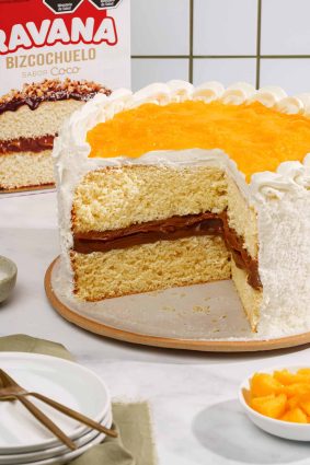 Torta de coco, dulce de leche y durazno con cobertura de crema y duraznos frescos.