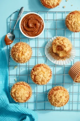 Muffins de coco con dulce de leche y crumble en bandeja azul.